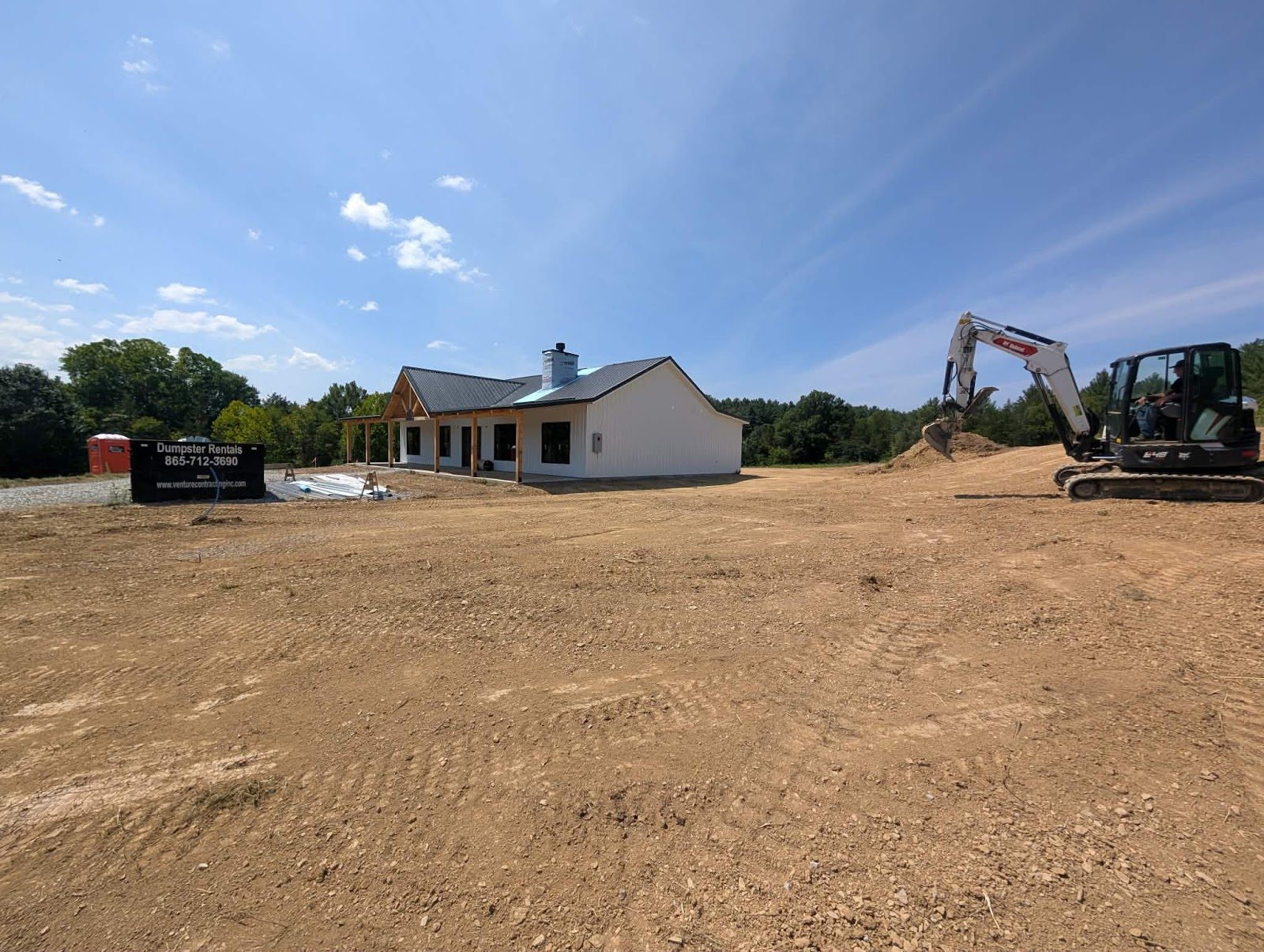 Graded home site with a Dirt DR excavator beside a new home